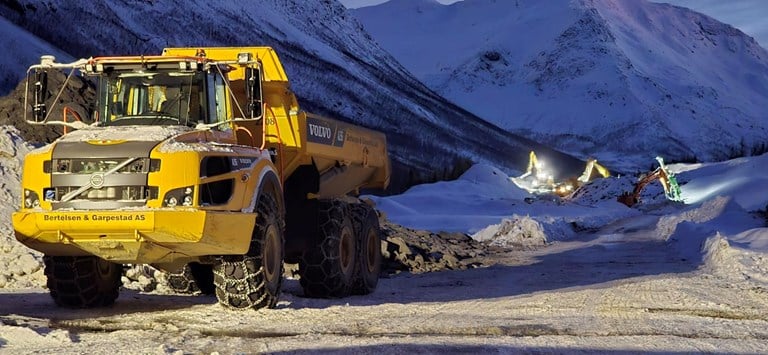 Bildet viser en dumper og tre gravemaskiner, som jobber med vegbygging på land i Ramfjorden. 