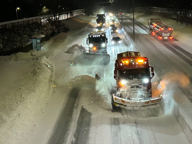 Bilde fra E6 i Trondheim tatt på kvelden torsdag 2. januar 2025. To brøytebiler i arbeid.