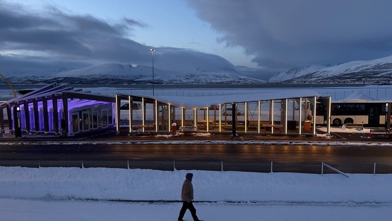 Bildet viser et av av de to venterommene med Kvaløya i bakgrunn. Taket på venterommene følger vinkelen på fjellformasjonene som ses på andre siden av fjorden. Byggenes silhuett etterligner og gjenspeil Kvaløyas silhuett slik øya ses fra terminalområdet. Speiler omgivelsene: Byggenes silhuett etterligner og gjenspeil Kvaløyas silhuett slik øya ses fra terminalområdet. Tegnet av arkitekt Michael Ritchel, Sweco.