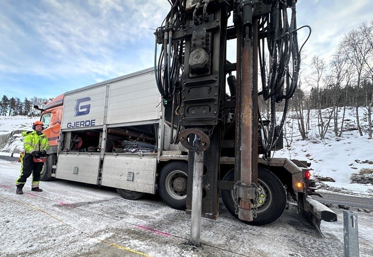 Bildet viser en anleggsmaskin som setter ned gjerdestolper til autovern. 