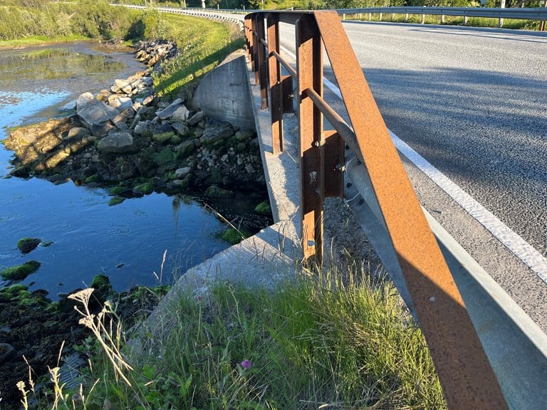 Bilde av rekkverket på brua over Storelva i Sørvik, som skal skiftes ut. Rekkverket er spinkelt og rustent. 