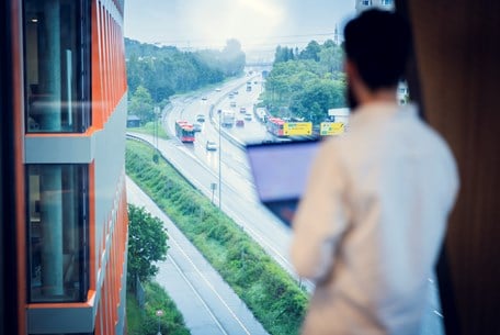 Kenneth står og ser ut av vinduet på en trafikkert vei