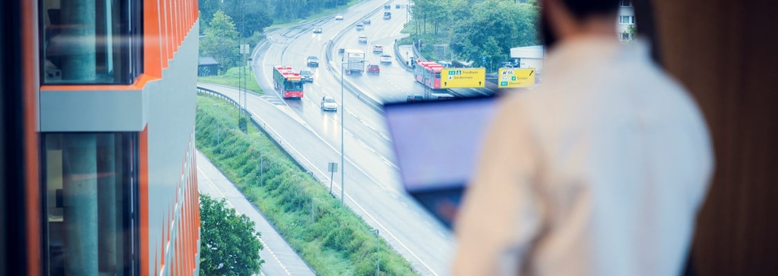 En mann som ser ut av vinduet på en trafikkert vei