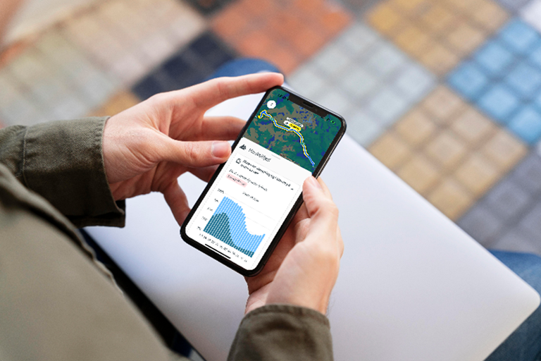 Bildet viser en person som holder en mobil i hånden. Mobilskjermen viser forsiden til appen Vegvesen trafikk.